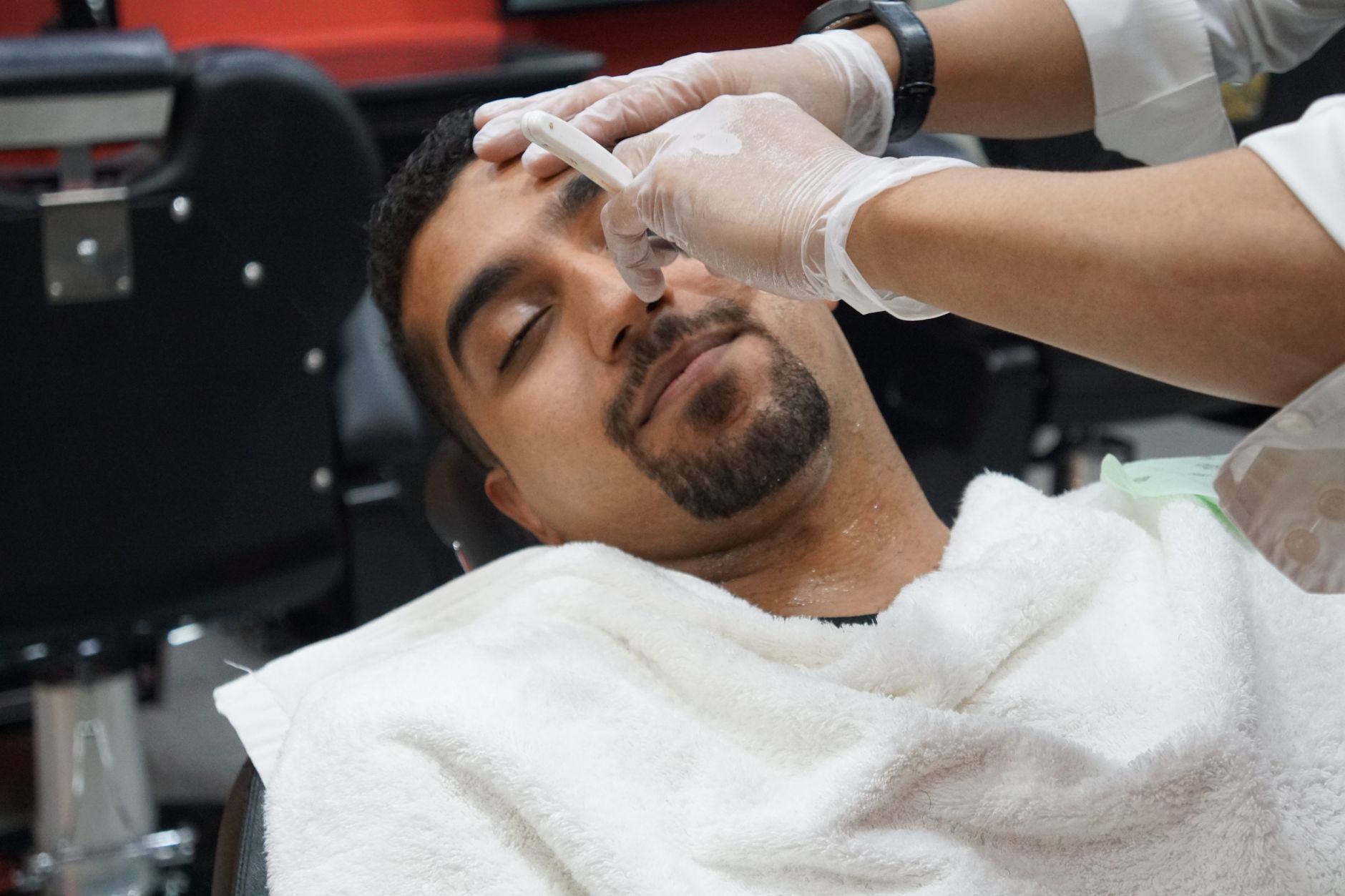 Barbero de Urban Barber afeitando a un cliente con navaja tradicional